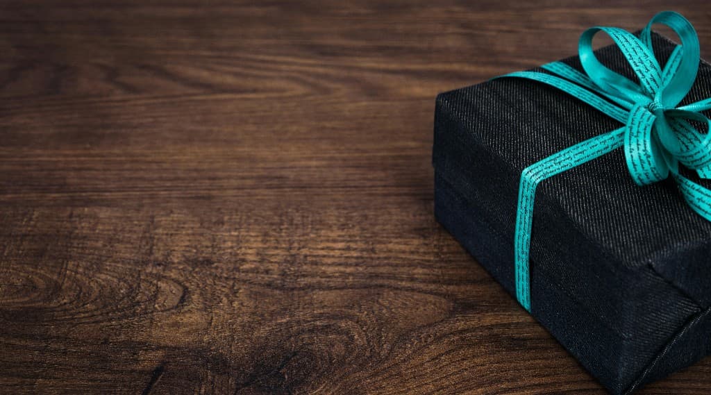 Gift box with turquoise ribbon on a wooden surface