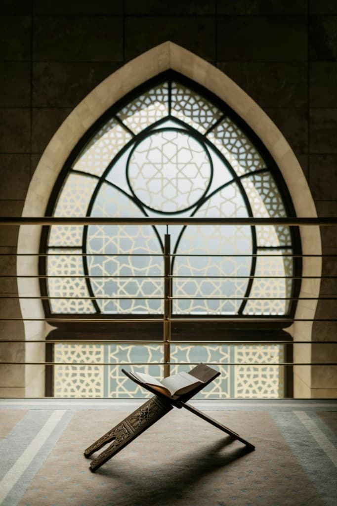 Open Quran on a rehal before an arched lattice window